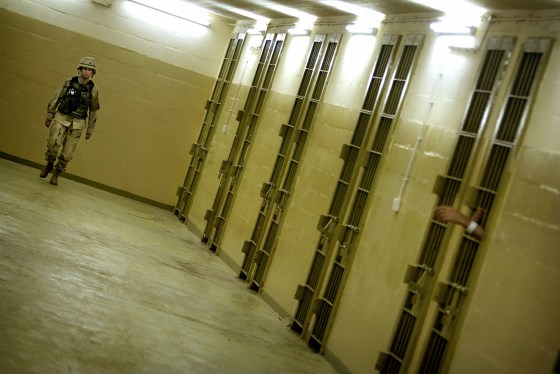 A U.S. soldier walks between cells with Iraqi detainees at the Abu Ghraib prison outside Baghdad on&nbsp;Monday.