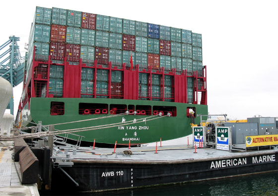 A container ship sits docked at the Port of Los Angeles Monday next to a barge carrying electrical equipment. Electrical power is routed from the barge to the ship so that it doesn't have to run its diesel engines while docked.