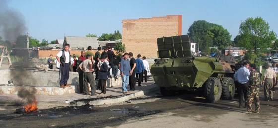Civilians look at a damaged armored pers