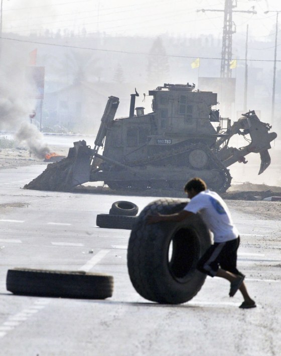 A Palestinian&nbsp;rolls a tire to erect a burning barricade to&nbsp;impede the advance of Israeli bulldozers and tanks Tuesday in the Gaza town of Beit Hanoun.&nbsp; 