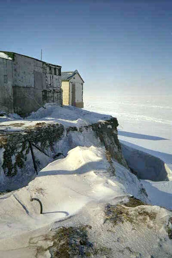 Seen during a winter freeze, buildings sit near a bluff eroded by storms in Shishmaref, Alaska. Locals fear the unprecedented erosion is tied to rising seas and global warming.