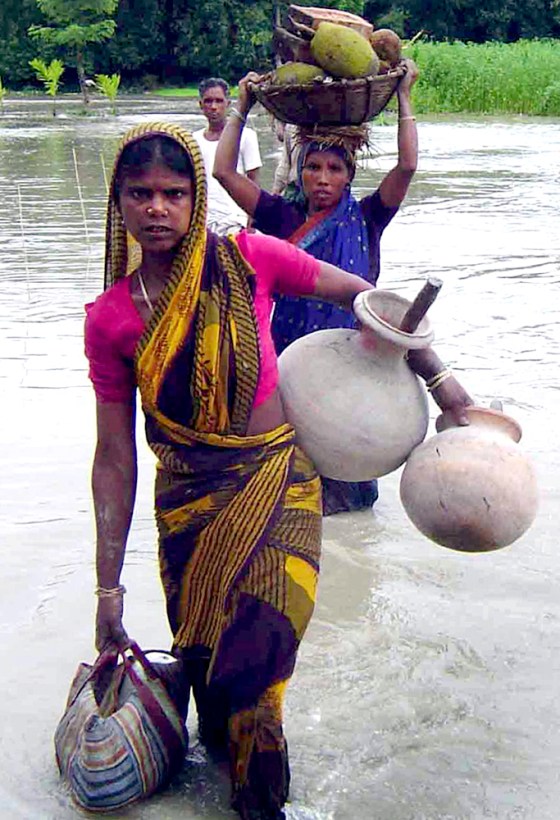 VILLAGERS WADE THROUGH A FLOODED AREA OF BALARAMPUR