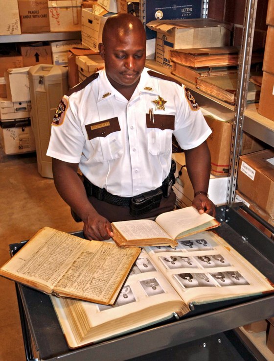 Montgomery County Chief Deputy Derrick Cunningham looks through pages of log books and booking photos Friday in the basement of the Montgomery, Ala., sheriff's office.