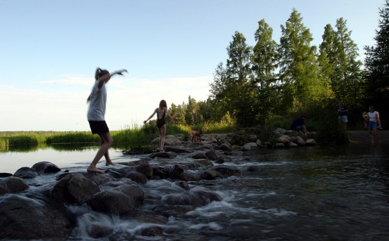 Children walk across the rocks at the outlet of Lake Itasca where the lake water becomes the Mississippi River in northern Minnesota. 