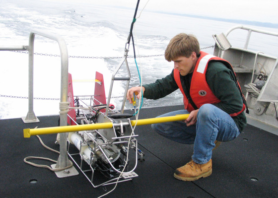 Crouched on the back of the research vessel Elakha, Oregon State University graduate student Anthony Kirincich on Tuesday attaches wings to a device called an Acrobat that controls the path of an array of instruments while they are towed behind the boat in the Pacific.