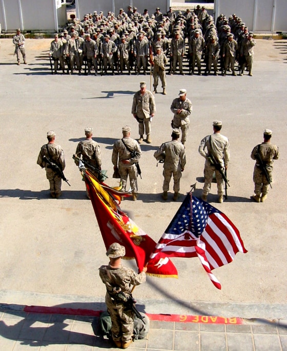 A Marine holds two flags — the Corps colors and the Stars and Stripes — during a ceremony for Gunnery Sgt. Elia Fontecchio, known as "Gunny," and Lance Cpl. Joseph Nice. The two Marines were killed while on patrol in western Iraq near the Syrian border.