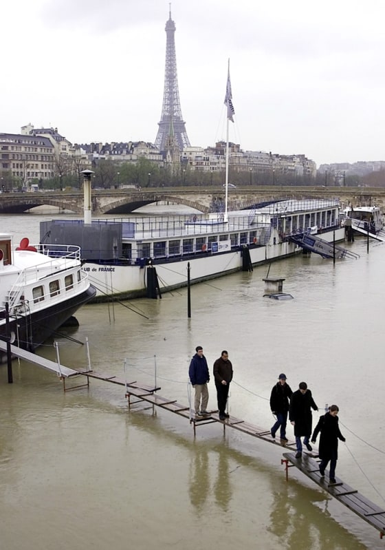 Europe's floods of 2001, in which 80 people died, are cited in a new report on what the continent can expect from global warming. Here, the River Seine in Paris burst its banks in March 2001, forcing people to walk on planks to get to boats.