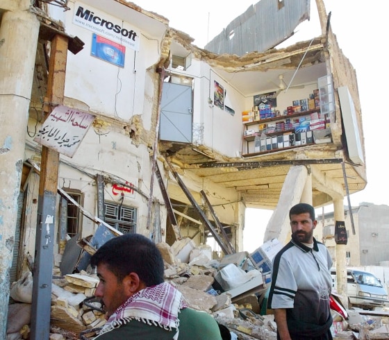 Iraqi Shi'ites look through destroyed shop on street leading to Najaf's Imam Ali shrine