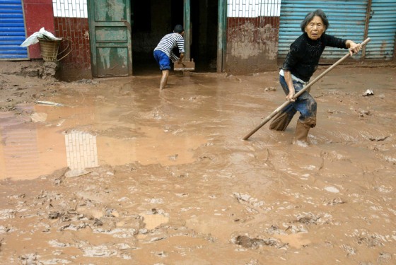 Local residents clear mud outside their home after floods receded in Kaixian