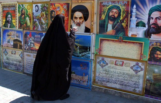 A woman reaches out to a picture of Grand Ayatollah Ali Husseini al-Sistani, posted alongside other Shiite religious figures in Baghdad, Iraq. Al-Sistani has been influential in pushing for early elections which would most benefit the county's large, majority-led political parties. 