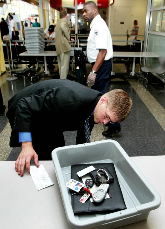 PASSENGER PLACES PERSONAL BELONGINGS IN TRAY AT AIRPORT CHECKPOINT