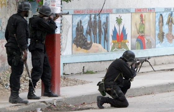 Haitian Police take position and shoot from a street close to an entrance to the pro-Aristide slum of Bel-Air, in Port-au-Prince, Haiti, on Friday.