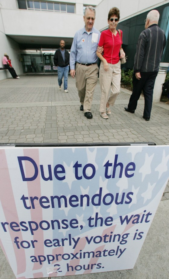 Two Gwinnett County, Ga., voters walk past a sign advising of a two-hour wait to cast early ballots as they leave the Gwinnett Justice and Administration Center in Lawrenceville, Ga., on Wednesday.