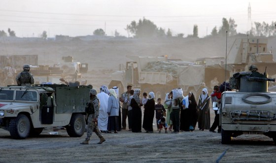 Refugees from Fallujah reach a US Marine checkpoint at the outskirts of Fallujah, Iraq, Wednesday, Nov. 10, 2004. Dead bodies lay on the streets of Jumhuriya, with dogs hovering around them, witnesses said. Residents ran out of food in a city that had its electricity cut.