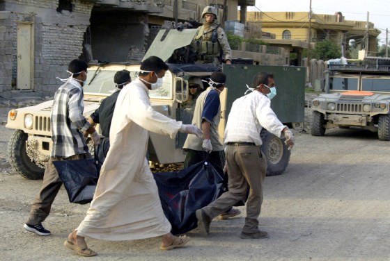 Iraqis carry a body in a bag as they wal