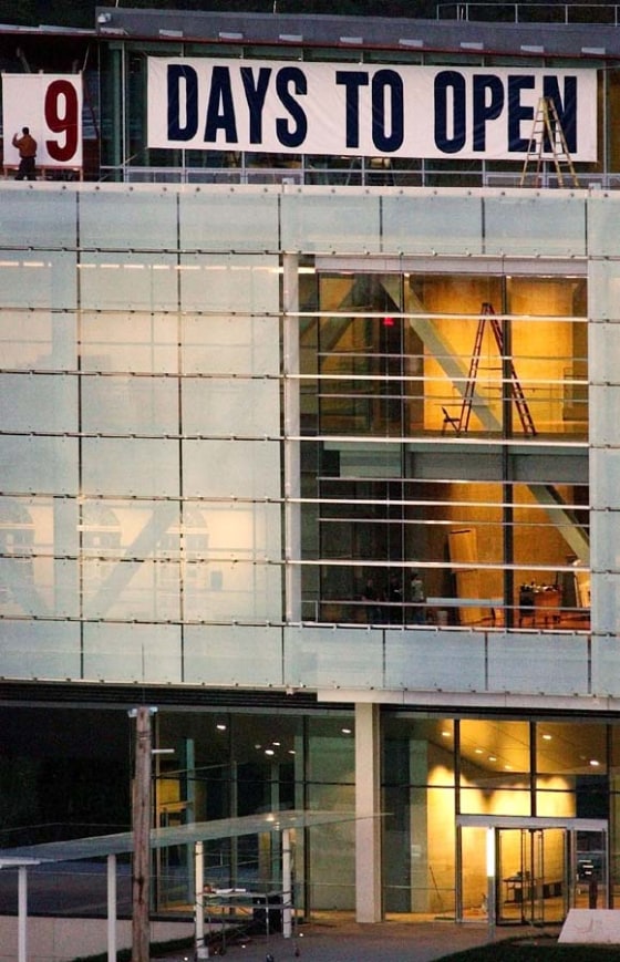 A worker, top left, changes the days-remaining sign on the roof of the Clinton Presidential Library to read \"9 Days to Open\", Nov. 8, 2004, in Little Rock, Ark.