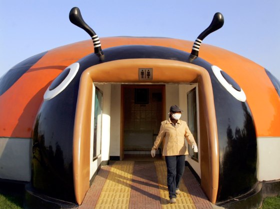 A Chinese cleaner emerges from a beetle-shaped toilet at a park in Beijing