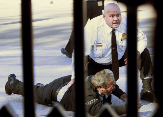 A uniformed member of the U.S. Secret Service guard is seen with a man on the ground who set himself on fire outside the White House fence on Pennsylvania Ave., on Monday.