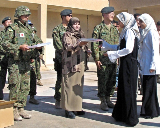 Japanese soldiers distribute school books to students in the southern city of Samawa
