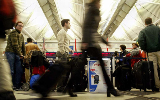 Passengers wait in line at the United Airlines terminal at Chicago's O'Hare Airport on November 27, 2002