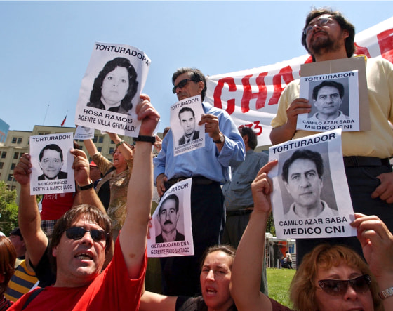 Former political prisoners and their relatives hold pictures of alleged torturers during a Monday demonstration in front of the presidential palace of La Moneda in Santiago, Chile.