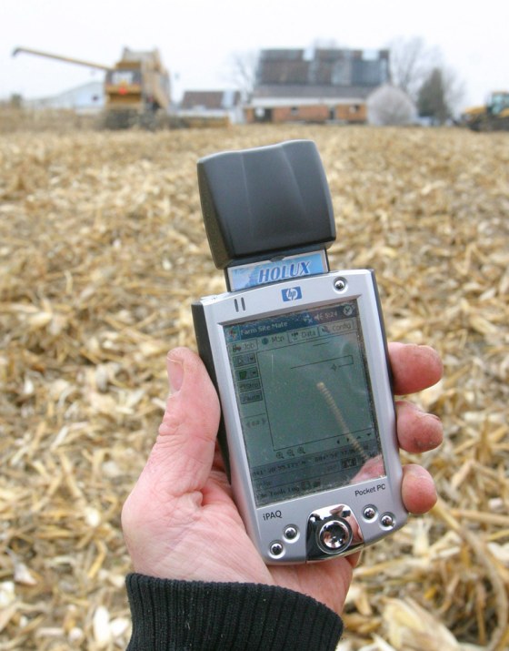 Farmer Brian Watkins holds a Pocket PC with a GPS receiver out in one of his Kenton, Ohio fields. He uses the device to create maps to record different seed and fertilizer combinations in the fields.