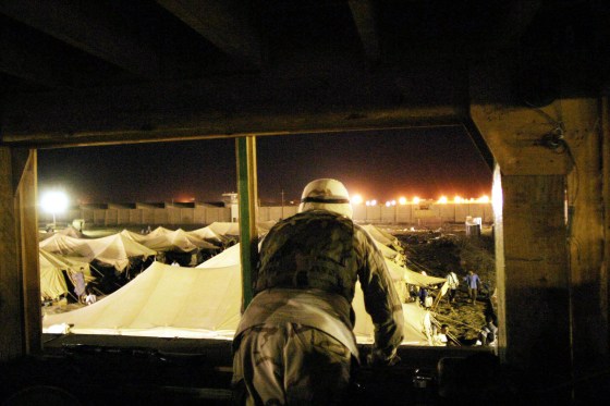 Military Police Spec. Duwayne Moore, 23, of Rockford, Ill., works in an Abu Ghraib watch tower overlooking tents surrounded by razor wire where detainees live.
