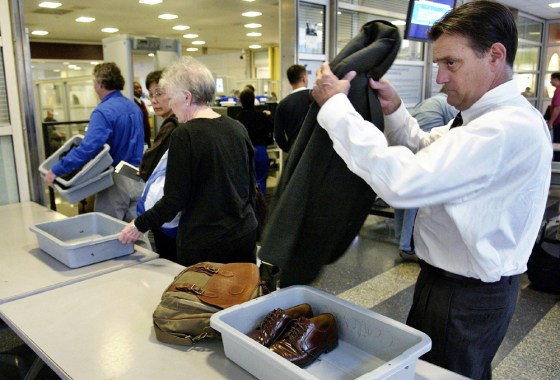 A passenger removes his coat as he passes through security screening at Reagan National Airport near Washington