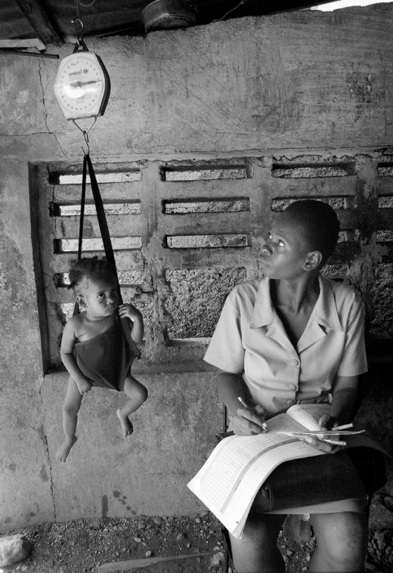 A toddler is weighed in a sling-scale by a heath worker from the UNICEF-assisted Martissant Community Clinic in Port-au-Prince, Haiti, in March 2004. 
