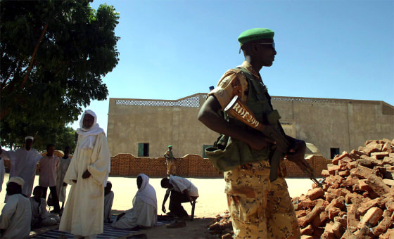 A soldier with the Rwandan Defense Force stands guard as fellow African Union troops meet with an Arab sheikh in Khara al Zawiyah, Sudan, in North Darfur.