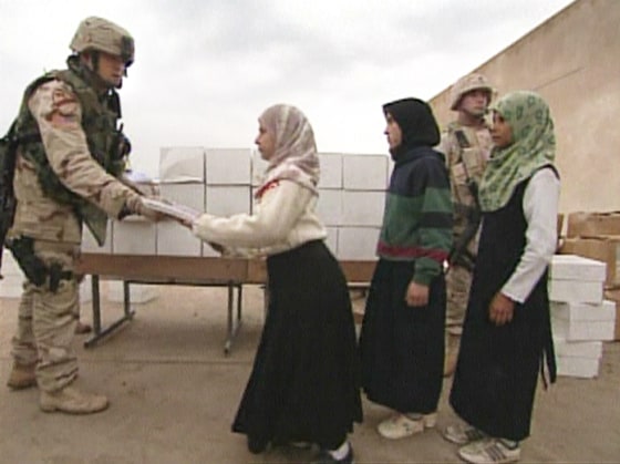 A soldier from 403rd civil affairs battalion hands out school supply kits to students of a primary school in central Iraq.