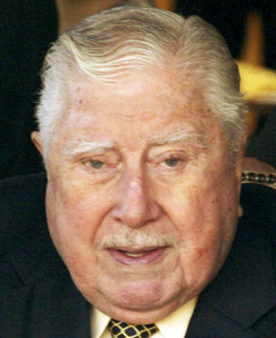 Former Chilean dictator Pinochet gets help from his bodyguards as he sits down in this file picture