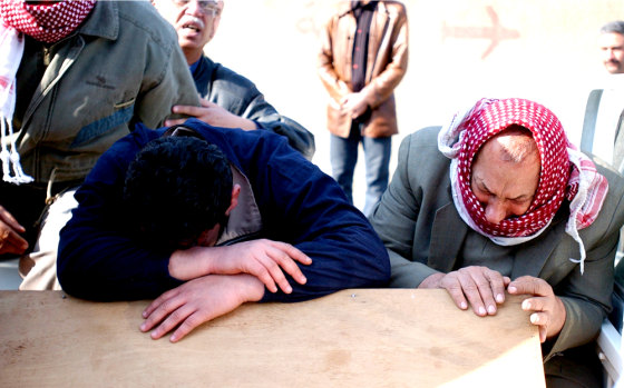An unnamed son, left, and a brother of assassinated Iraqi Deputy Communications Minister Qassim Mehawi cry over his coffin in Baghdad after he was killed Thursday. 