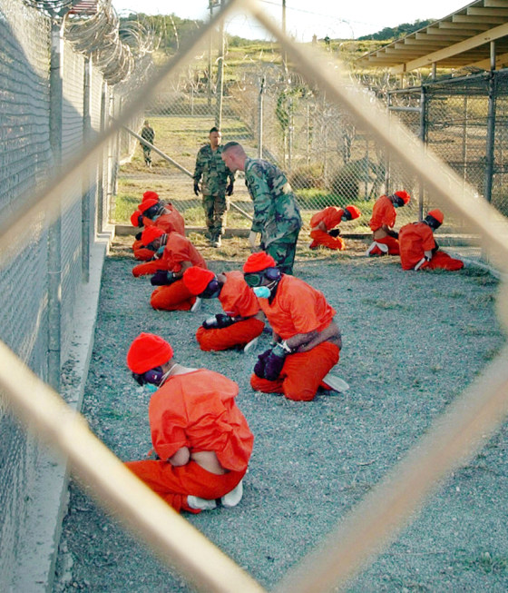 Suspected Taliban and al-Qaida detainees sit in a holding area at Camp X-Ray at Guantanamo Bay, Cuba, in a Jan. 11, 2002, file photo.