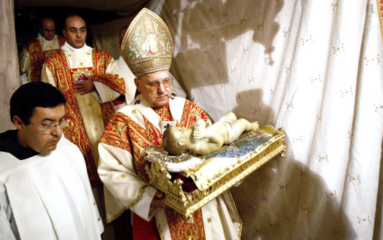 The Latin Patriarch of Jerusalem Michel Sabbah carries a statue of Baby Jesus down into the grotto, the site where Christians believe Jesus Christ was born, early Saturday&nbsp;at the Church of the Nativity in the West Bank town of Bethlehem.