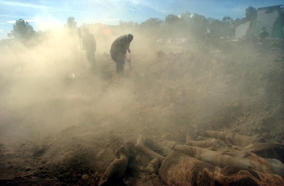 In a mass grave, Iranian relief workers pour dust on the bodies of people killed in a massive earthquake that hit the ancient city of Bam in December 2003.