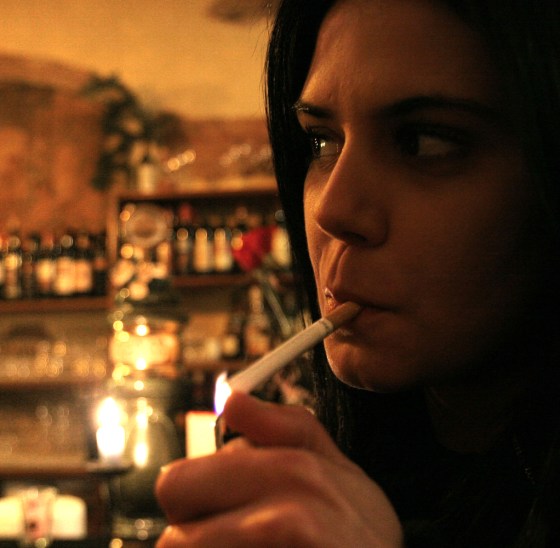A woman lights a cigarette in a bar in downtown Rome Sunday. Smokers in Italy took their last puffs in smoky bars and trattorias hours before the start of one of Europe's toughest laws against smoking in public places.