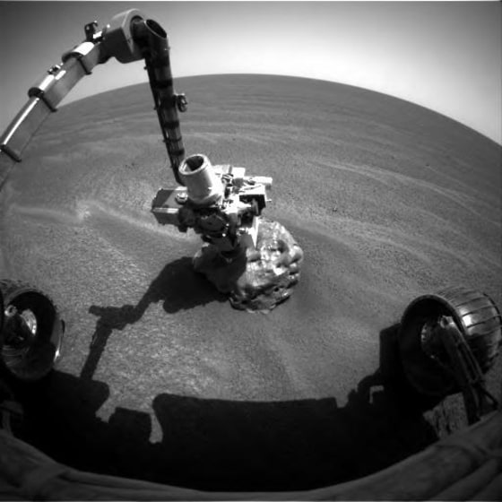 The Opportunity rover extends its instrument-laden robotic arm to take a close look at "Heat Shield Rock," which could be a meteorite on the Martian surface.