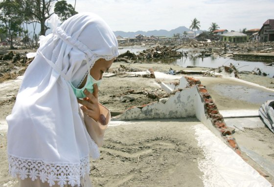 Woman stands on the remains of her parents' house washed away by tsunami in Banda Aceh