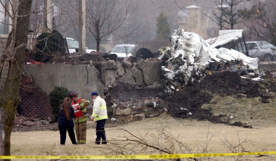 Emergency workers talk near the site of a twin-engine plane crash in an affluent neighborhood of Overland Park, Kan., on Friday.
