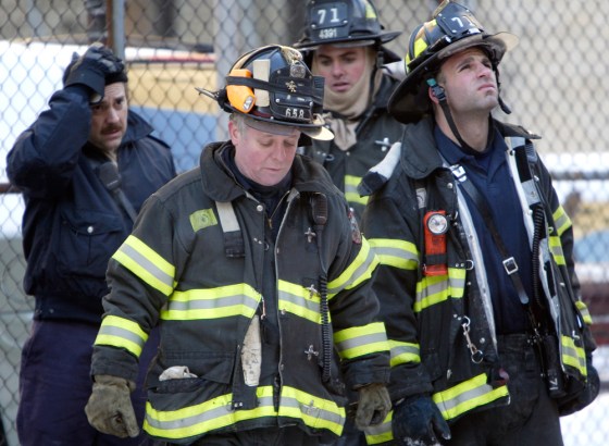 New York City fire crews look up at the building where two firemen were killed and four others badly injured Sunday in an early morning fire in the Bronx.