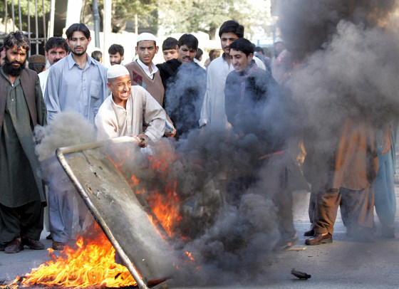 Supporters of a slain Sunni Muslim cleric burn road signs during violence in Karachi