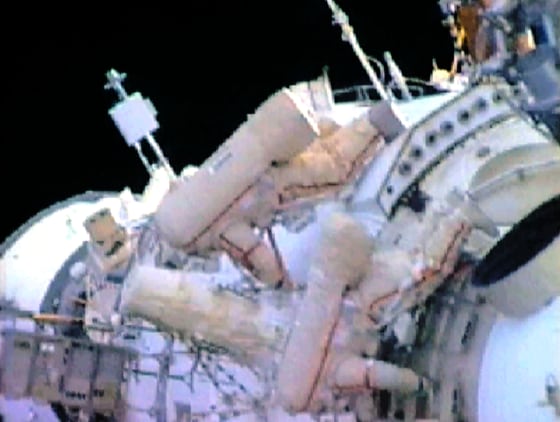 Astronaut and cosmonaut perform space walk at space station