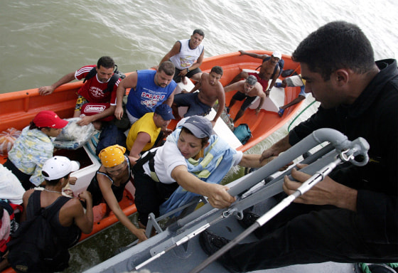 Venezuelans climb aboard a navy ship during an evacuation after torrential rains in Vargas state
