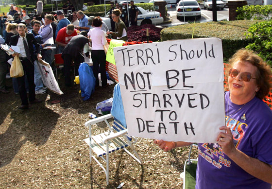 A supporter of brain-damaged Florida woman Terri Schiavo holds poster in front of the the Woodside Hospice in Florida