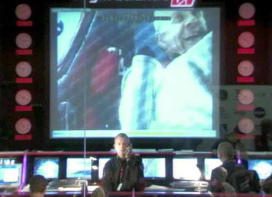 GlobalFlyer mission controllers in Kansas communicate Wednesday with solo pilot Steve Fossett, seen in a cockpit view displayed on a giant screen in the background.