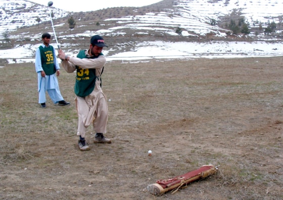 Afghan student Mohammed Ayub takes a swing on the course of the Kabul Golf Club as classmate Sayed Mohammed looks on.