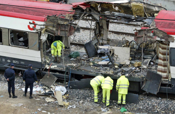 Spanish railway workers and police examine the debris of a destroyed train at Madrid's Atocha railway station on March 12, 2004. A year after terrorists killed 191 people, both U.S. and Spanish officials say that there is no evidence that al-Qaida leadership authorized or even knew of the plan.