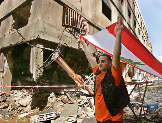 An anti-Syrian protester carries a Lebanese flag on Sunday at the site of the explosion in an industrial zone of the mainly Christian neighborhood in Beirut.