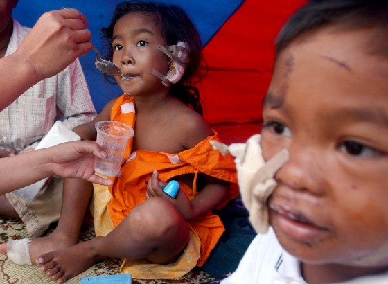 Yumni, 6, is fed powdered food by her mother as her brother Ramadhan, 4, looks on, in Gungung Sitoli on Nias Island, Indonesia, on Thursday. Yumni, who sustained serious injuries to her ear and hand, which doctors are considering amputating, was later flown to Medan for medical treatment.